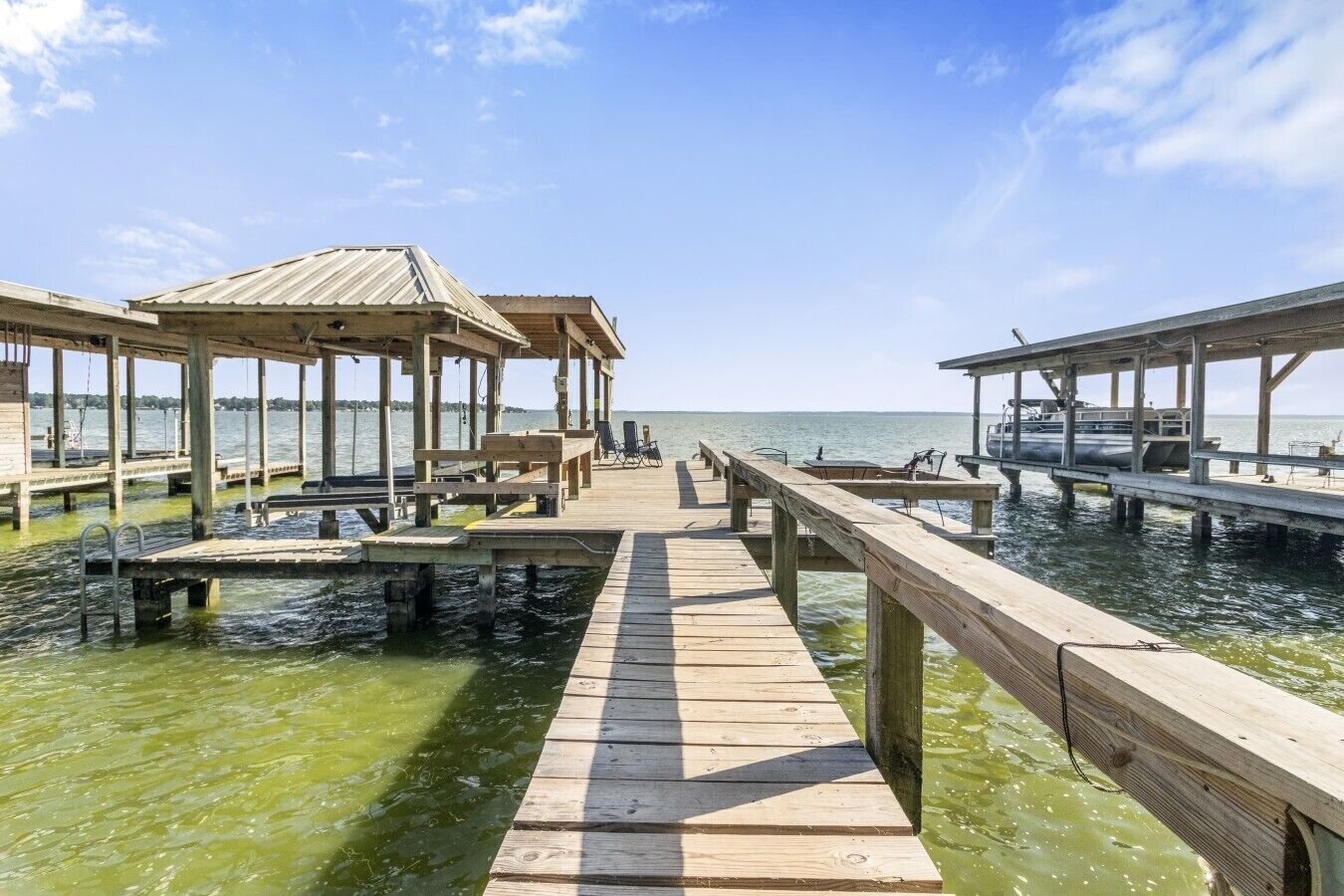 A wooden pier extending into calm water with a clear sky.