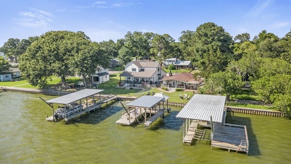 A lakeside property with docked boats, a house, and surrounding greenery.