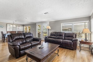 A living room with two leather sofas, a wooden coffee table, and a dining area with a table and chairs. - Lakefront Livingston Retreat w Dock & Fire Pit! (Livingston)