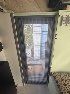Ein Zimmer mit einer Schiebetür, die zu einem Außenbereich führt, einem Bett, einem kleinen Tisch und einem Schrank.