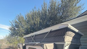 En campingvogn med et teltlignende tag, flere vinduer og en dør.