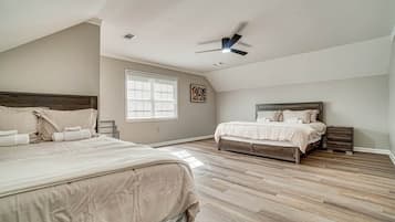 A bedroom with two beds, a ceiling fan, and a window with blinds.