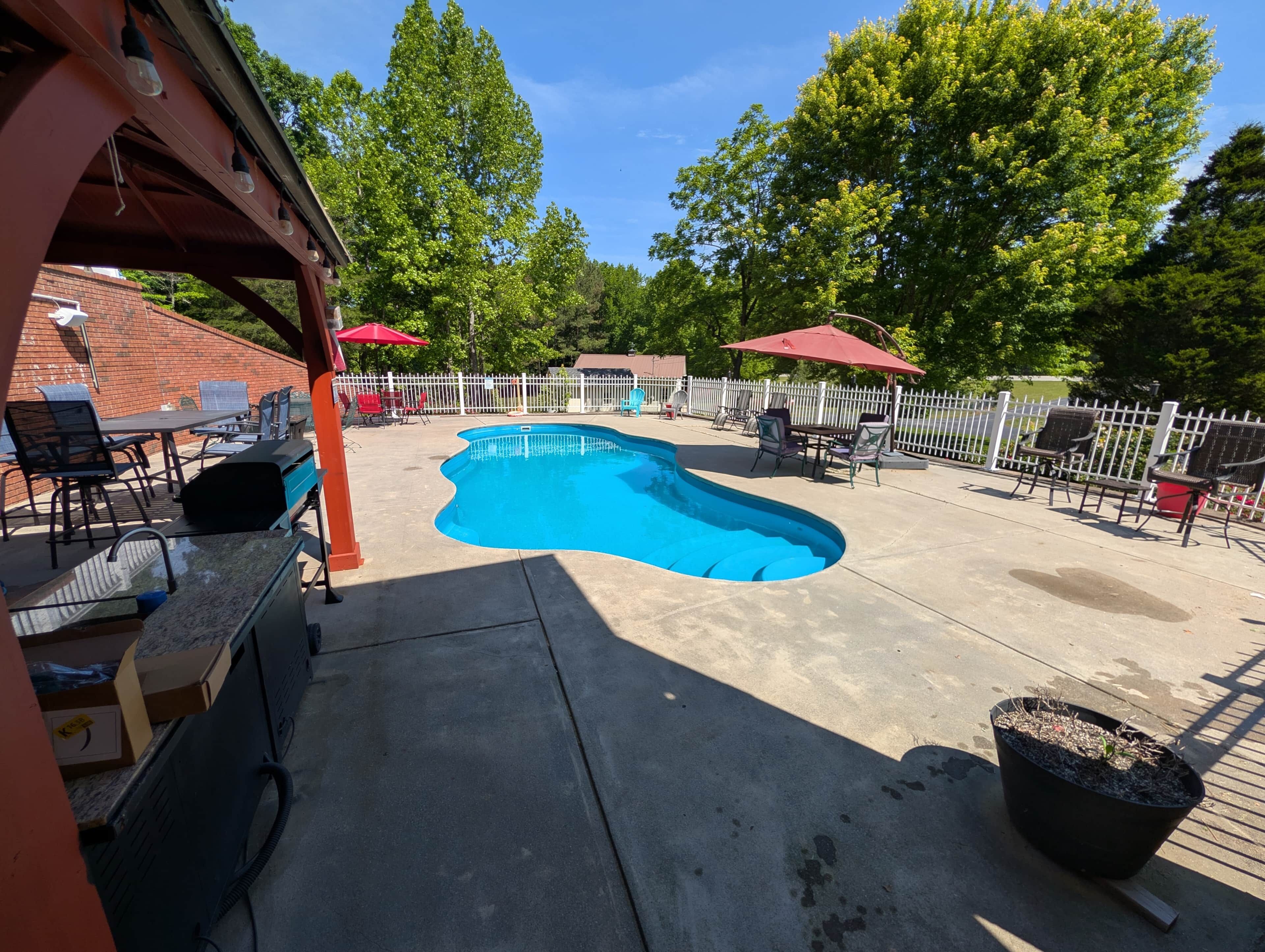 A backyard with a swimming pool, outdoor furniture, and a covered patio area.