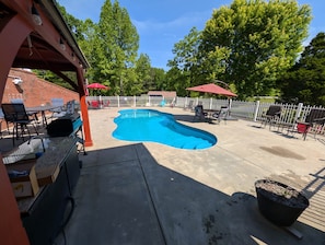 Ein Garten mit Swimmingpool, Gartenmöbeln und einer überdachten Terrasse.