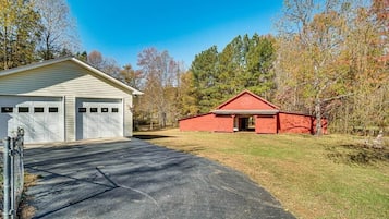 A residential property with a garage, a red barn, and a driveway leading to a house.
