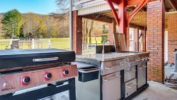 An outdoor kitchen with a grill, a sink, and a built-in oven.