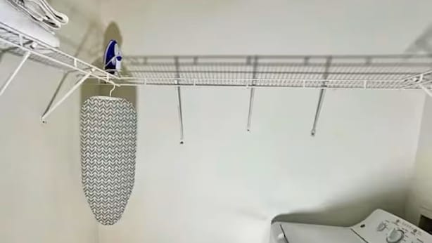 A laundry area with a washing machine, a drying rack, and a patterned ironing board.
