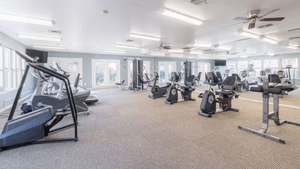 A gym with various exercise equipment, large windows, and ceiling fans. - Pleasant King 1Bed 1Bath Near Med Center with Pool (Houston)