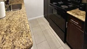 A kitchen with granite countertops, a stove, a microwave, and dark wooden cabinets. - Pleasant King 1Bed 1Bath Near Med Center with Pool (Houston)