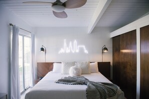 Et moderne hotelværelse med seng, loftsvifte og en by-lysinstallation.