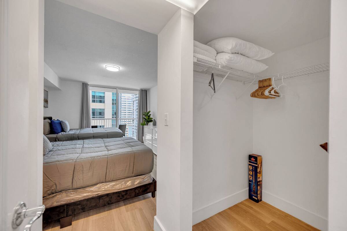 Un dormitorio moderno con una cama grande, un armario con espacio para colgar y vistas a la ciudad.