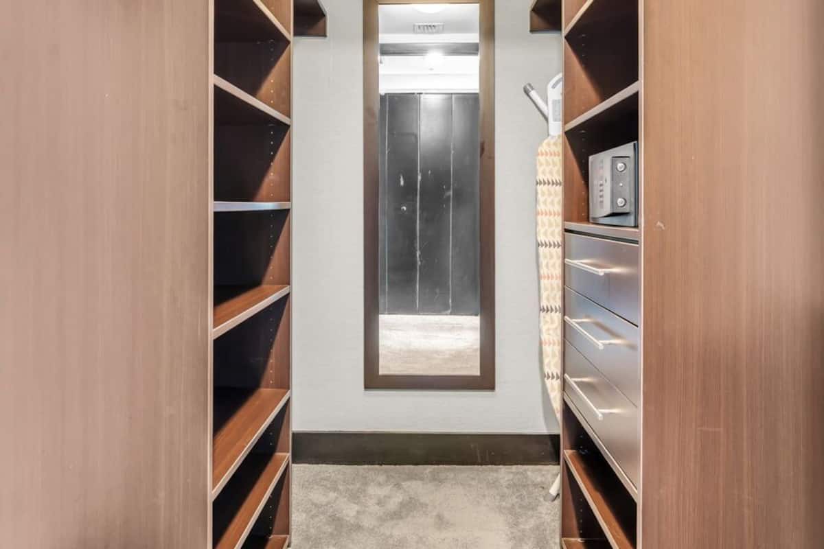 A walk-in closet with built-in shelving, a window, and a ceiling light.