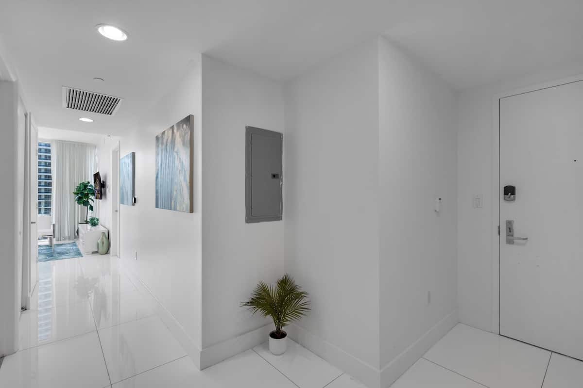 A modern hallway with white walls, a potted plant, and a door.