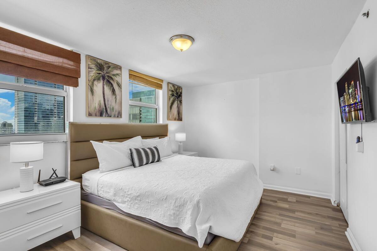 Un dormitorio moderno con una cama grande, una mesita de noche, una lámpara y obras de arte en las paredes.
