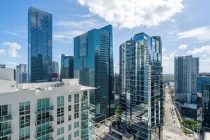 A cityscape with modern high-rise buildings, including a prominent glass skyscraper and a building with a unique facade. - The Club at Brickell Bay (Miami)