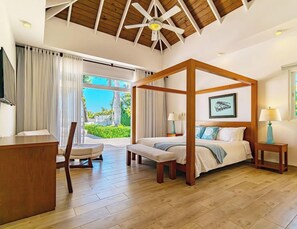 Ein Schlafzimmer mit Himmelbett, Schreibtisch, Stuhl und Blick ins Freie.