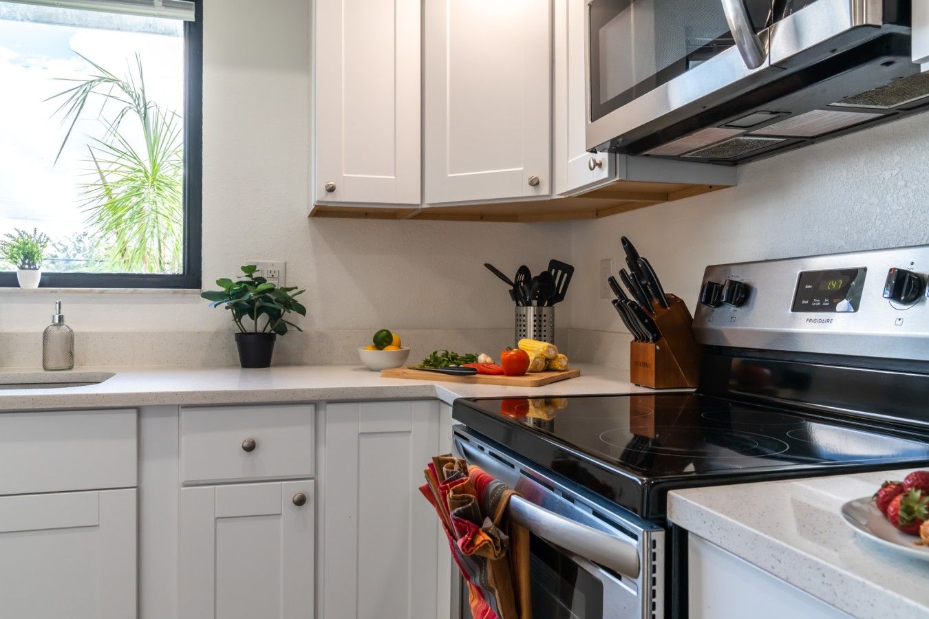 A kitchen with white cabinets, a stainless steel oven, and a microwave above.