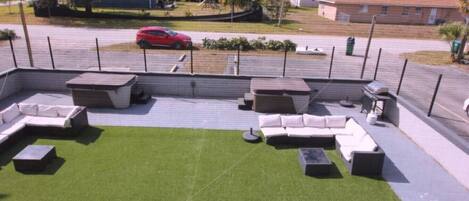 A rooftop patio with outdoor seating, a small lawn, and a view of the neighborhood.