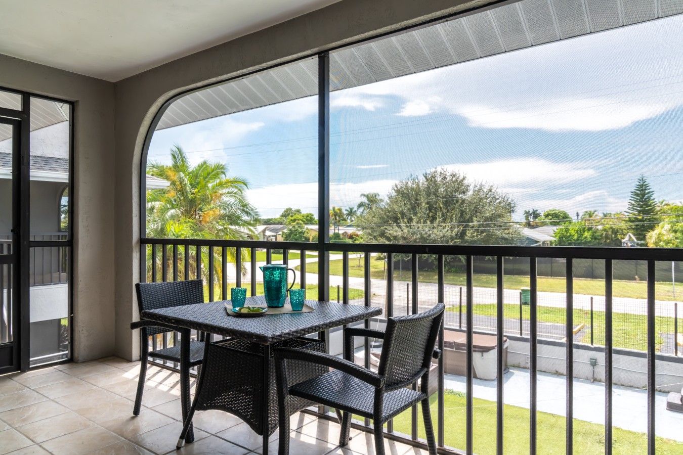 A balcony with a table and chairs, a view of the street, and a clear sky.