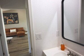 Une salle de bain avec un lavabo blanc, un miroir et un flacon de savon.