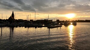 A marina with boats docked, a church spire, and a sunset over the water. - Baltic Sea time-out - near Darß - relaxation in the midst of nature (Pruchten)