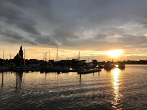 A marina with boats docked, a church spire, and a sunset over the water. - Baltic Sea time-out - near Darß - relaxation in the midst of nature (Pruchten)