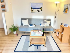 A living room with a sofa, coffee table, and a lamp. - Baltic Sea time-out - near Darß - relaxation in the midst of nature (Pruchten)