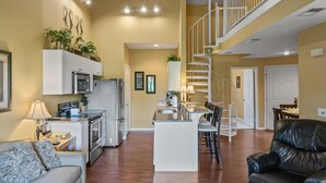 A spacious living area with a kitchen, dining space, and a staircase leading to an upper level.