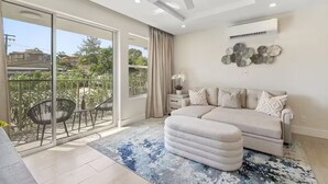 Una sala de estar moderna con un sofá, una mesa de centro y un balcón con sillas.