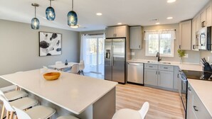 Una cucina moderna con isola centrale, elettrodomestici in acciaio inossidabile e illuminazione a sospensione.