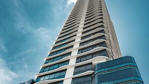 A tall, modern skyscraper with a curved facade and large windows. - Deluxe Loft with Ocean View (Panamá)
