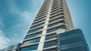 Een hoog, modern gebouw met een gebogen gevel en grote ramen.