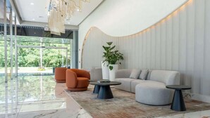 A modern lobby with a curved wall, seating area, and a large window offering a view of greenery. - Chic 1-Bedroom with Urban Views in Panama (Panamá)