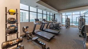 A gym with treadmills, weight machines, and exercise balls, with large windows and a city view. - Chic 1-Bedroom with Urban Views in Panama (Panamá)