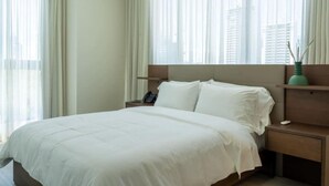 Una habitación de hotel con una cama, una mesita de noche, un teléfono y una ventana con cortinas.