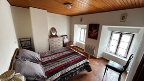 Makuuhuone, jossa on sänky, lipasto, tuoli ja ikkunat.