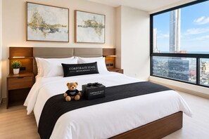 A hotel room with a large bed, two nightstands, a window with a city view, and two abstract paintings on the wall. - Costa del Este 2BR Apartment | Pool & City Views (Panamá)