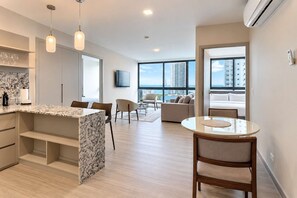 A modern apartment with a kitchen, dining area, and living room. - Costa del Este 2BR Apartment | Pool & City Views (Panamá)