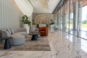 Eine moderne Lobby mit einer gebogenen Couch, einem runden Couchtisch und einem Blumentopf.
