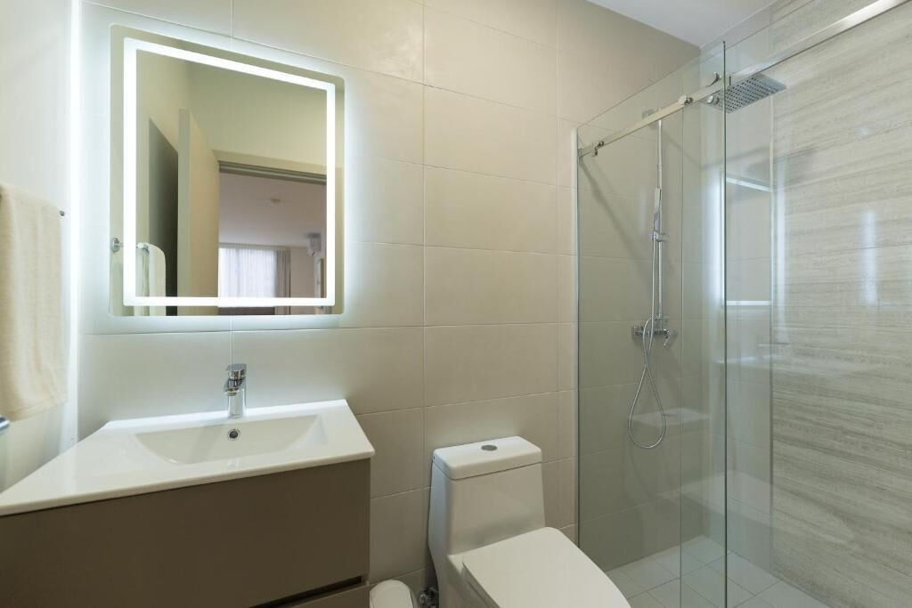 A bathroom with a glass shower enclosure, a white sink, and a toilet.