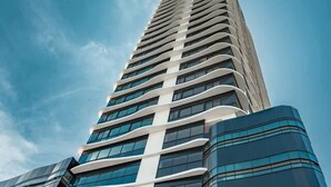 A tall, modern building with a curved facade and large windows. - Coastal View Executive Studio in Panama (Panamá)