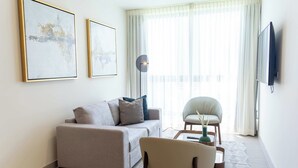 A modern living room with a sofa, armchair, coffee table, and artwork on the wall. - Serviced 2 bedroom with Ocean Views in Costa del Este (Panamá)