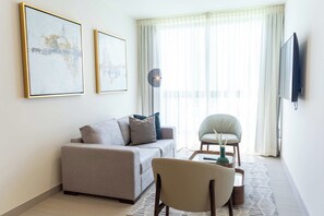 Een moderne woonkamer met een bank, fauteuil, salontafel en kunstwerk aan de wand.
