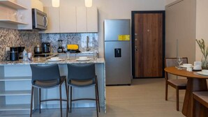 A modern kitchen with a marble countertop, stainless steel appliances, and a dining area with a wooden table and chairs. - Serviced 2 bedroom with Ocean Views in Costa del Este (Panamá)