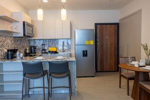 Een moderne keuken met een marmeren aanrechtblad, roestvrijstalen apparatuur en een eethoek met een houten tafel en stoelen.