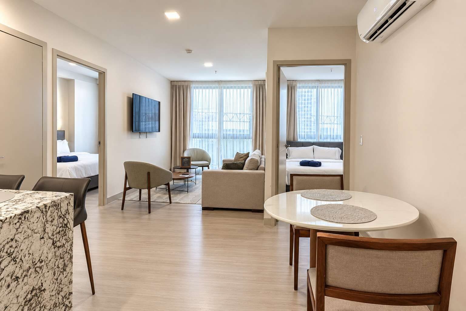 Ein Hotelzimmer mit Essbereich, einer Couch, einem Fernseher und einem Bett.