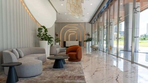 A modern lobby with a curved sofa, a round coffee table, and a potted plant.