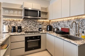 A modern kitchen with a built-in microwave, coffee maker, toaster, and a sink with a faucet. - Costa del Este 2-Bedroom Corporate Rental | 2 Baths, Water Views & Pool (Panamá)