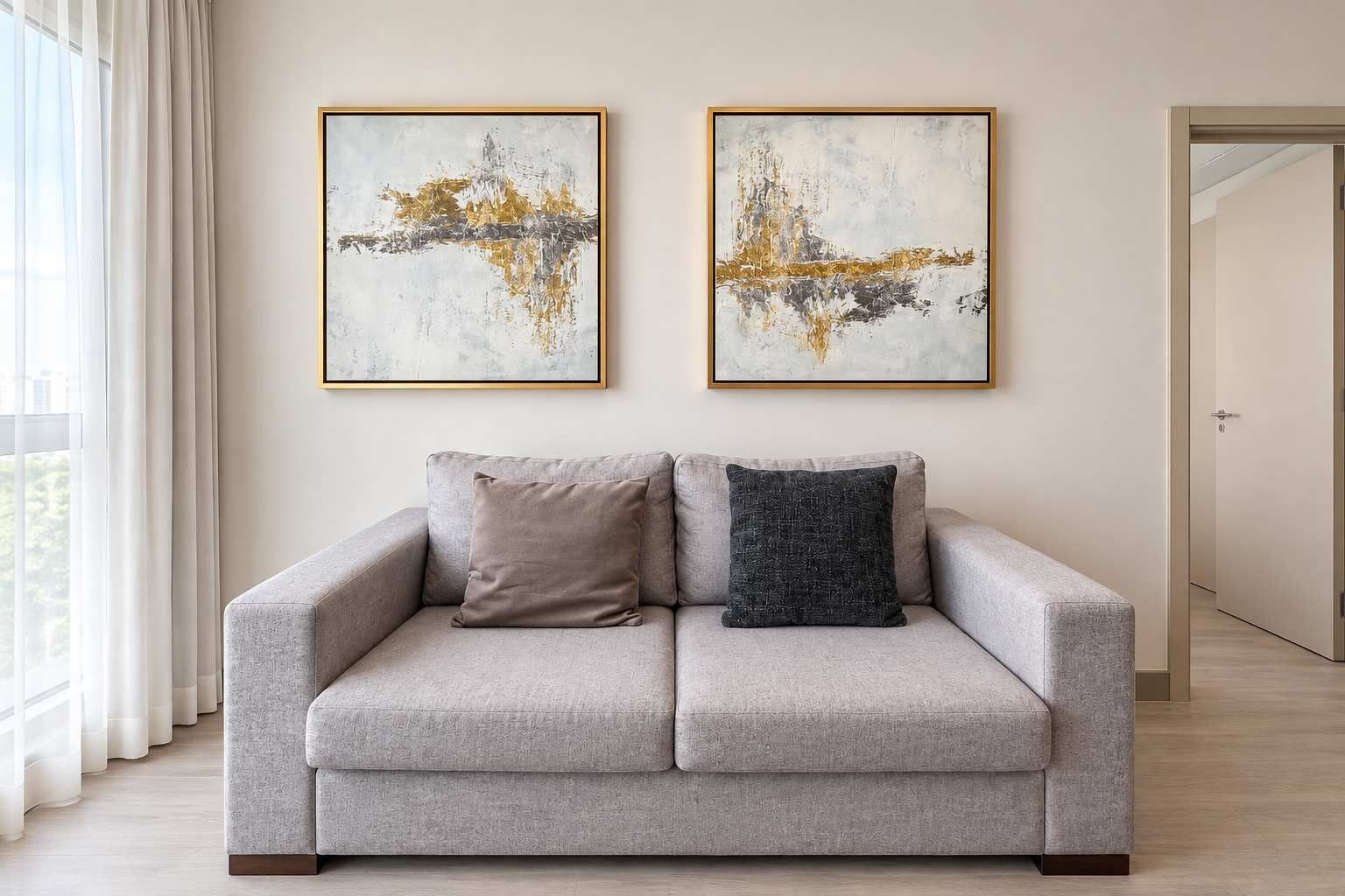 Ein sofas in neutralen Farben mit zwei Kissen, ein großes Fenster mit transparenten Vorhängen und zwei abstrakte Gemälde an der Wand.