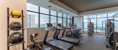 Academia com esteiras, aparelhos de musculação e bolas de exercício.